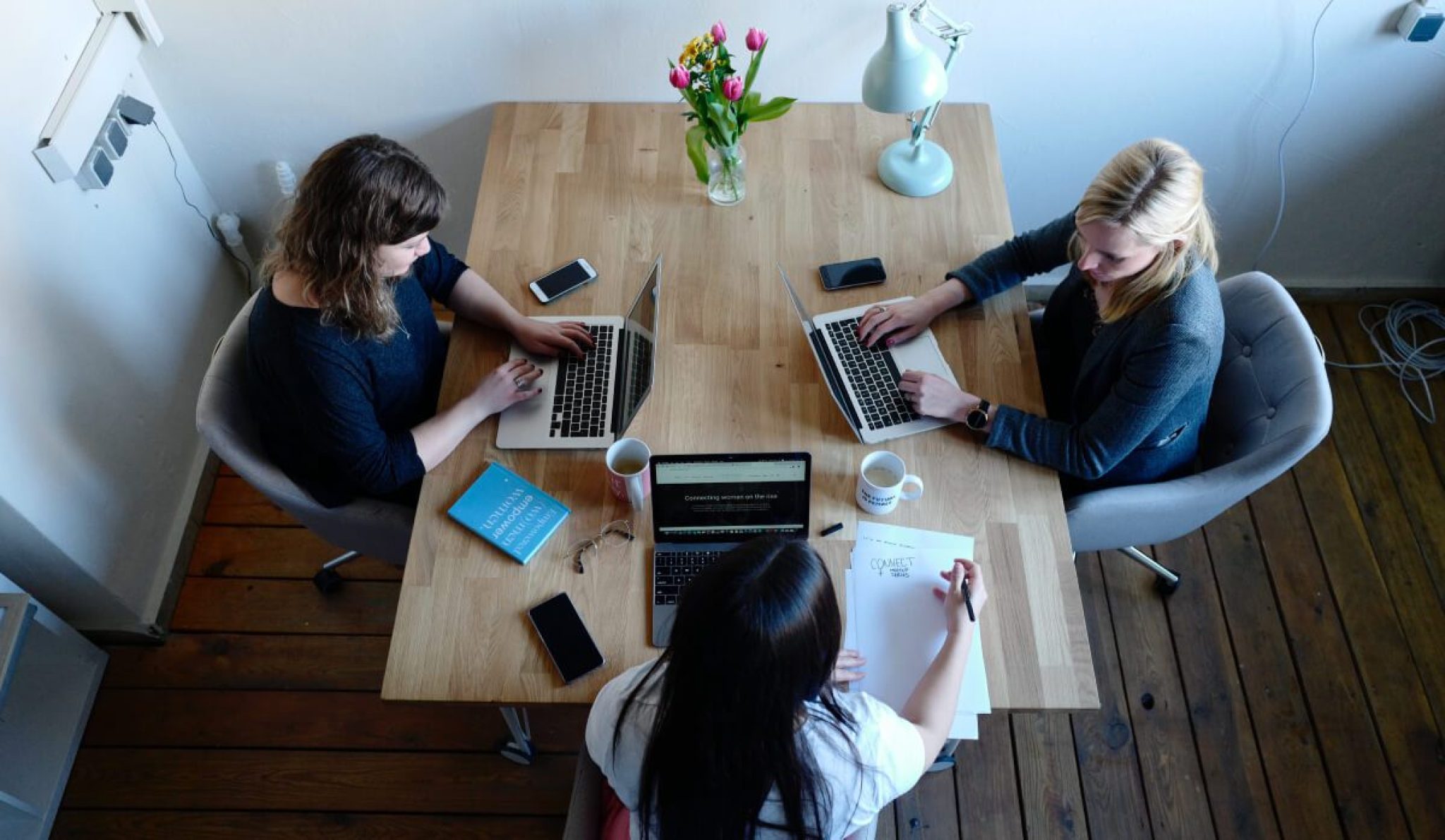 a group of women sitting at a table with laptops